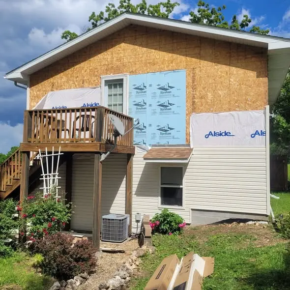 Old siding removed, showing sheathing, house wrap, and insulation board